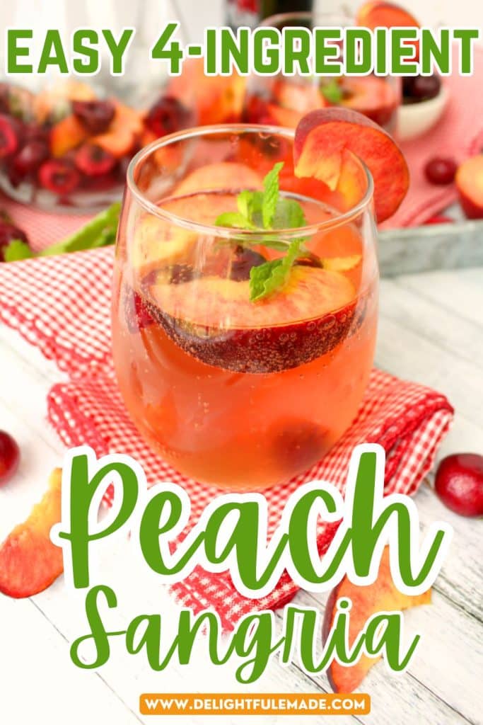 Glass of peach sangria topped with fresh peach slices, fresh cherries and a sprig of fresh mint.