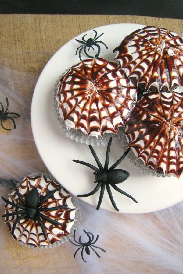 These fun Halloween Spider Web Cupcakes are the perfect treat for your ghouls and goblins. These delicious chocolate cupcakes are topped with a vanilla frosting and chocolate syrup spider webs. Fantastic for a Halloween classroom treat or party snack!