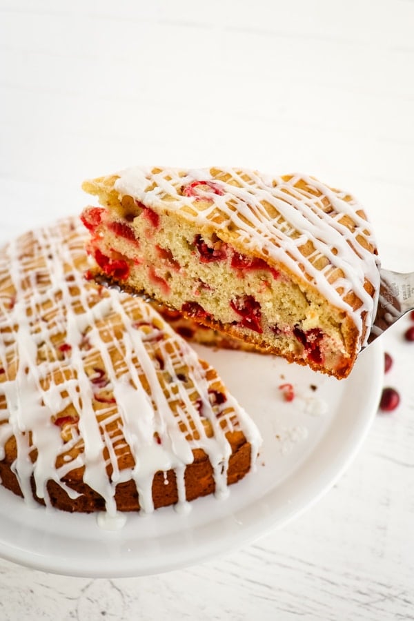Slice of cranberry coffee cake being lifted from the cake platter.