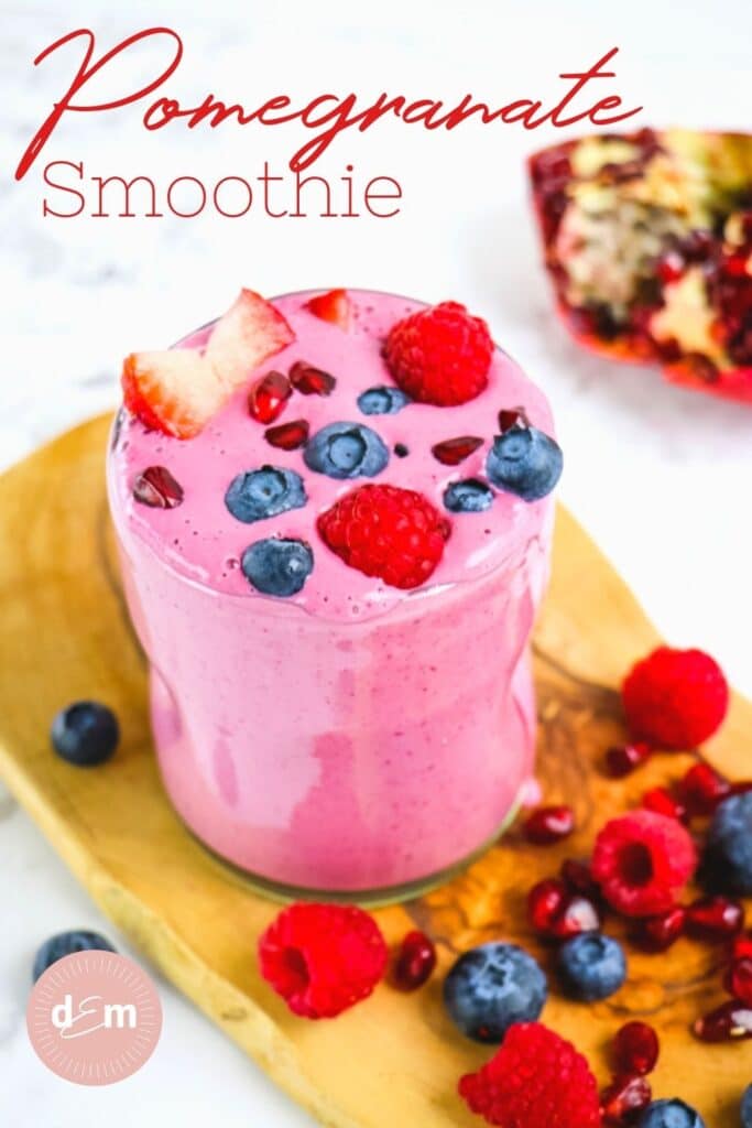 Pomegranate smoothie in glass, garnished with fresh berries and pomegranate arils.