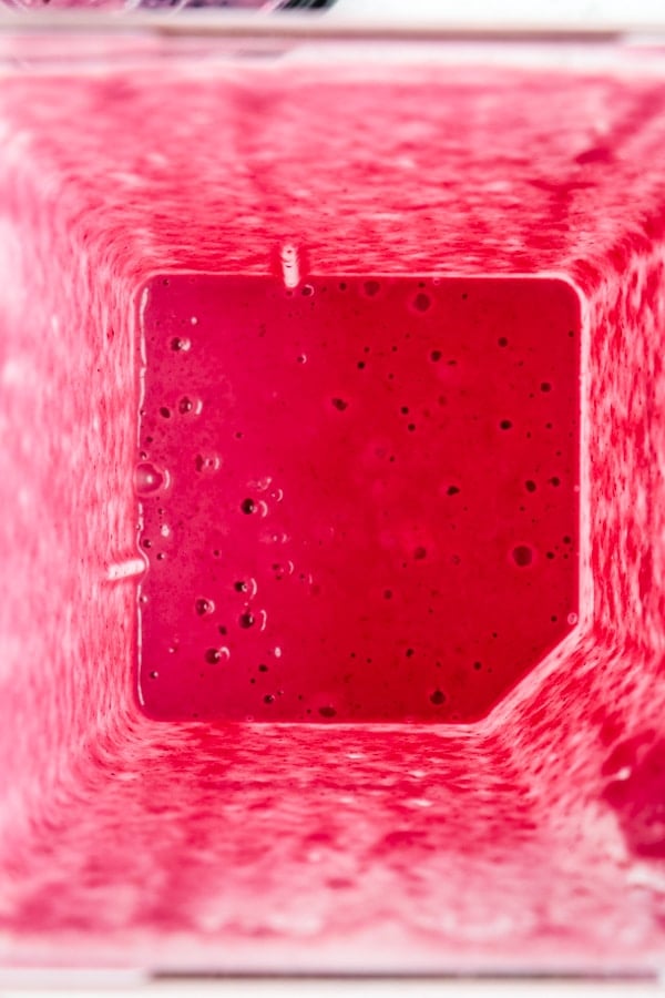 Blended pomegranate smoothie, that is bright pink, looking down into jar of blender.