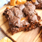 Cake mix turtle brownies on board, garnished with chocolate chips and caramels.