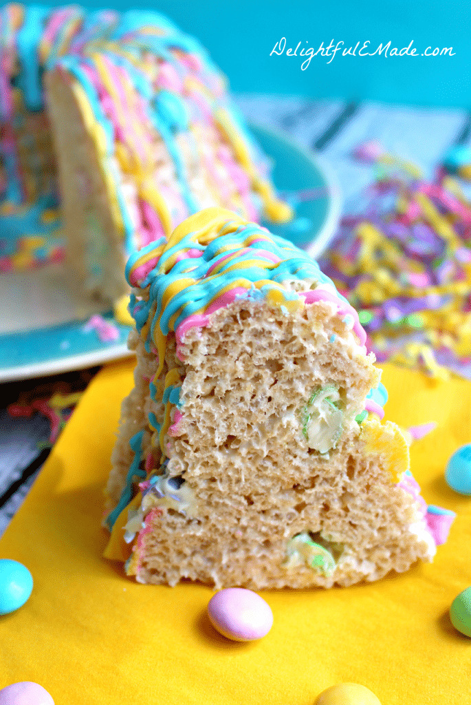 This rice krispie cake recipe will be your new favorite spring treat!   Super easy to make, this rice krispie cake is made in a bundt pan, and loaded with colorful spring M&M's candies, and drizzled with pretty pastel candy melts.