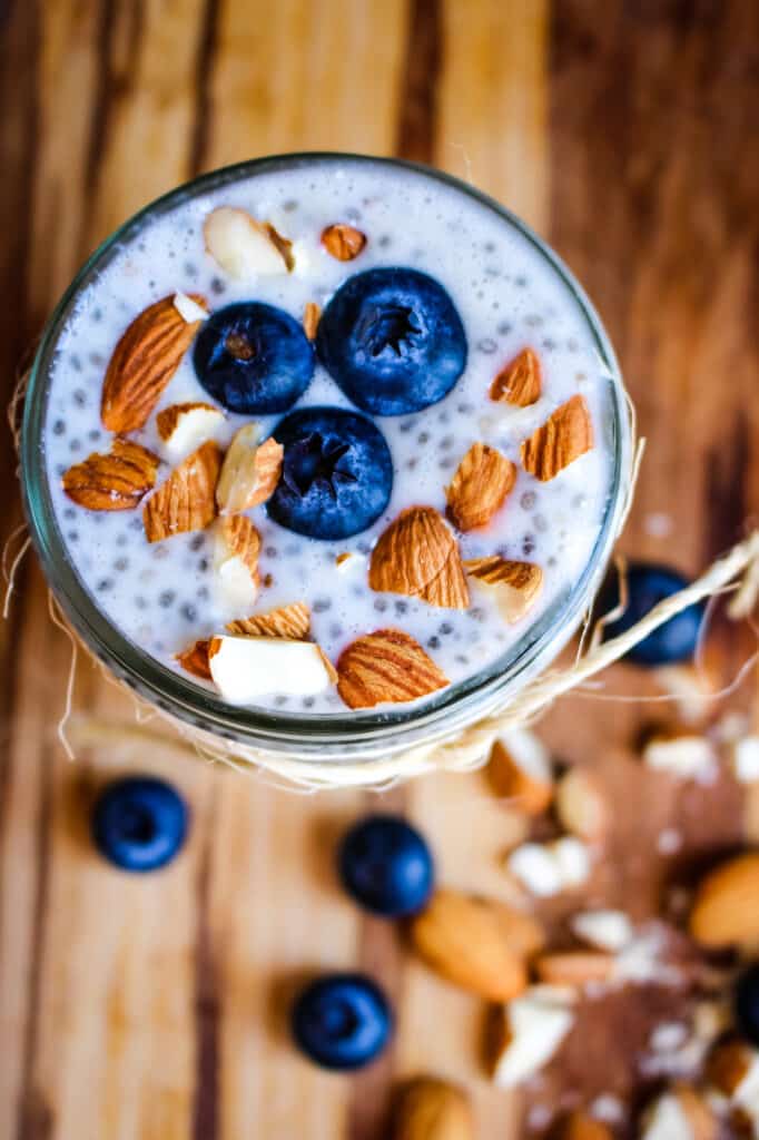 Overhead shot of blueberry chia pudding in a mason jar topped with fresh blueberries and chopped almonds.