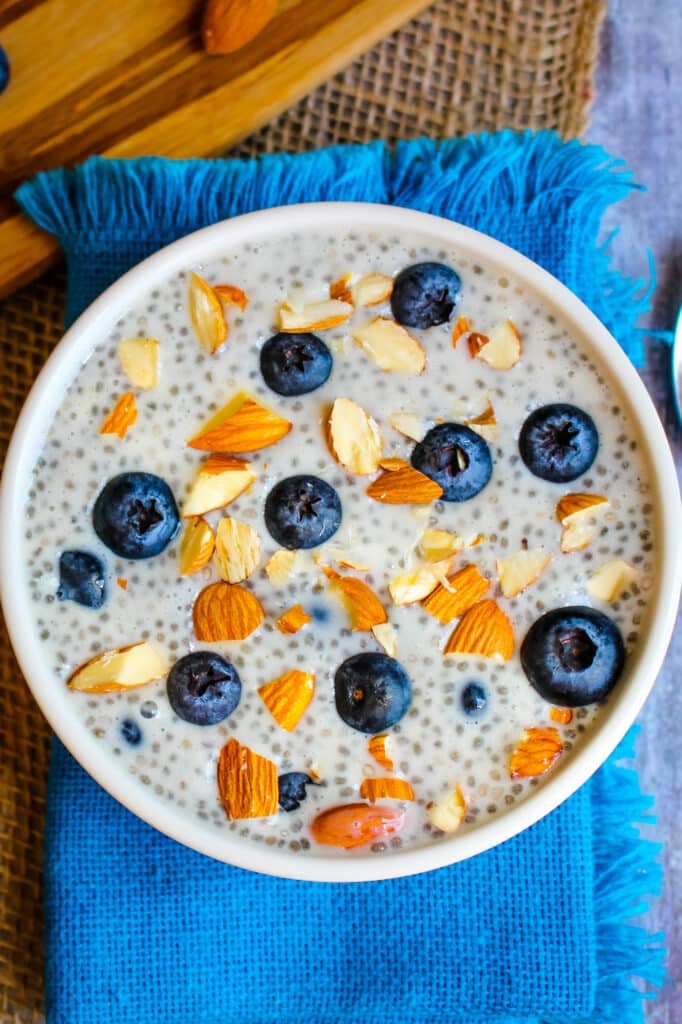 Overnight chia pudding in white bowl topped with fresh blueberries and chopped almonds.