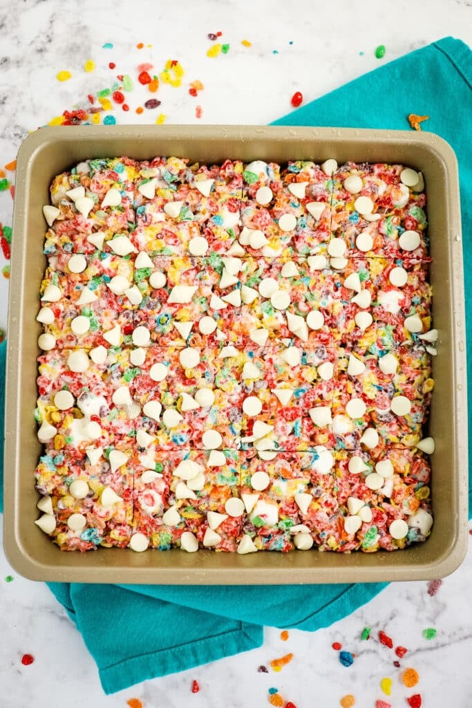 Fruity pebbles treats cut into squares in a pan.
