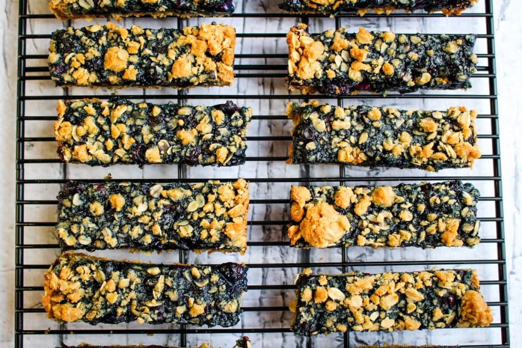 Blueberry oatmeal bars with brown sugar oatmeal crumble topping cut into long bars on a cooling rack.