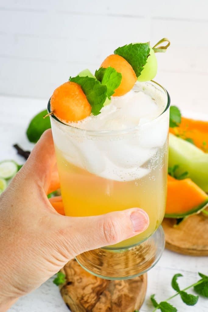 Melon mojito drink with ice held in hand.