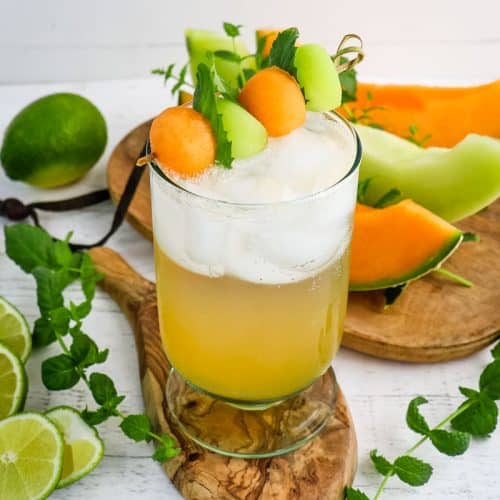 Melon mojito garnished with melon balls and fresh mint leaves.