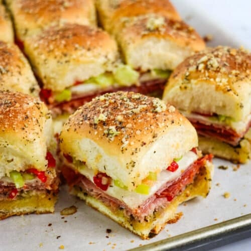 Italian slider recipe cut into individual sandwiches on a sheet pan.