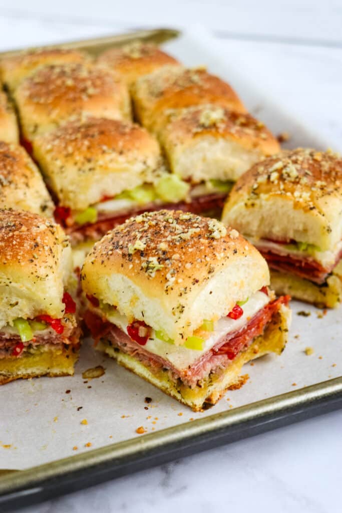 Italian slider recipe cut into individual sandwiches on a sheet pan.