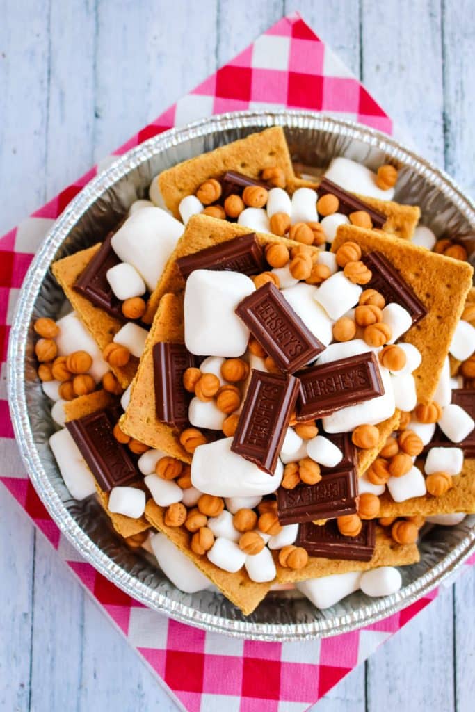 Campfire smores in pan layered with graham crackers, marshmallows, chocolate bars and caramel bits.