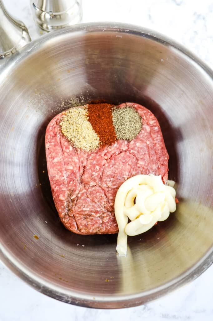 Ground beef in a mixing bowl, with mayo, Worcestershire sauce and spices.