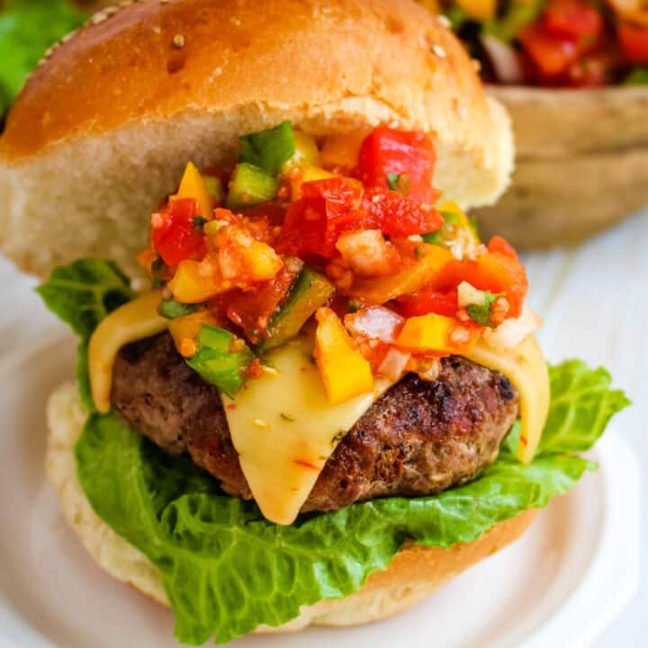 Salsa burger on a sesame bun with lettuce and topped with pepper jack cheese and chunky salsa.