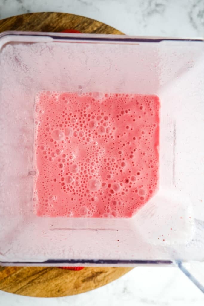 Blended ingredients for a strawberry frappuccino in a blender, top down view.
