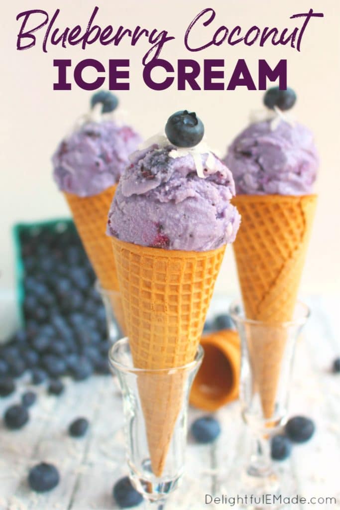 Three ice cream cones topped with a single scoop of blueberry ice cream, and topped with coconut and fresh blueberries.