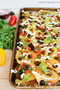 Football food at its finest! These Loaded Steak Nachos have everything you love stacked on top - loads of cheese, seasoned steak, tomatoes, onions, guacamole and more! Eat 'em while their hot and make another batch for the second half!
