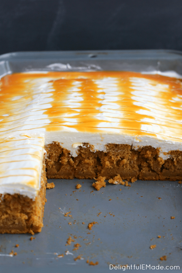 Pumpkin caramel poke cake in a pan that has been sliced into squares.