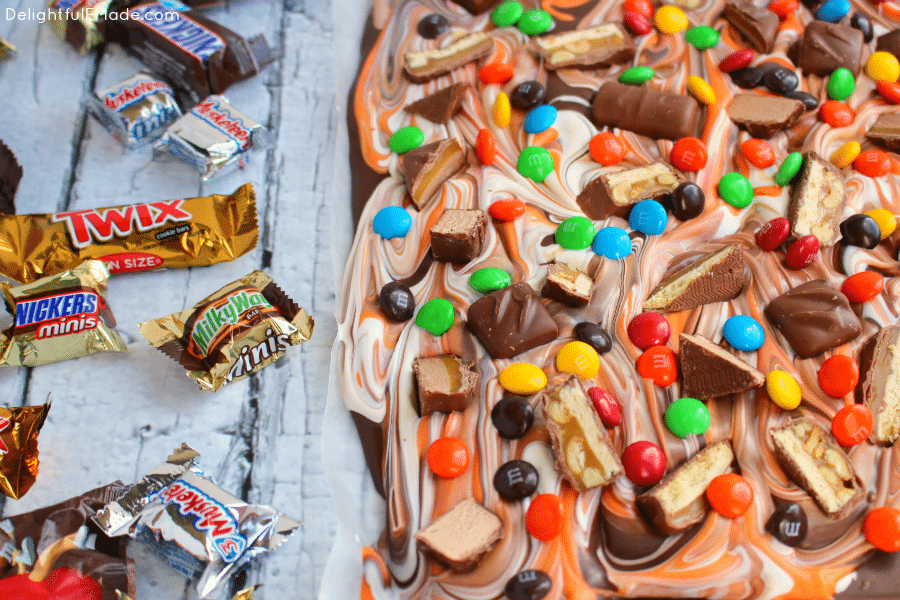 The perfect way to enjoy all your favorite candy in one glorious bite! My Halloween Candy Bark is made with delicious chocolate, white and orange candy melts, and bejeweled with loads of candy! A great treat to add to any Halloween Boo basket!