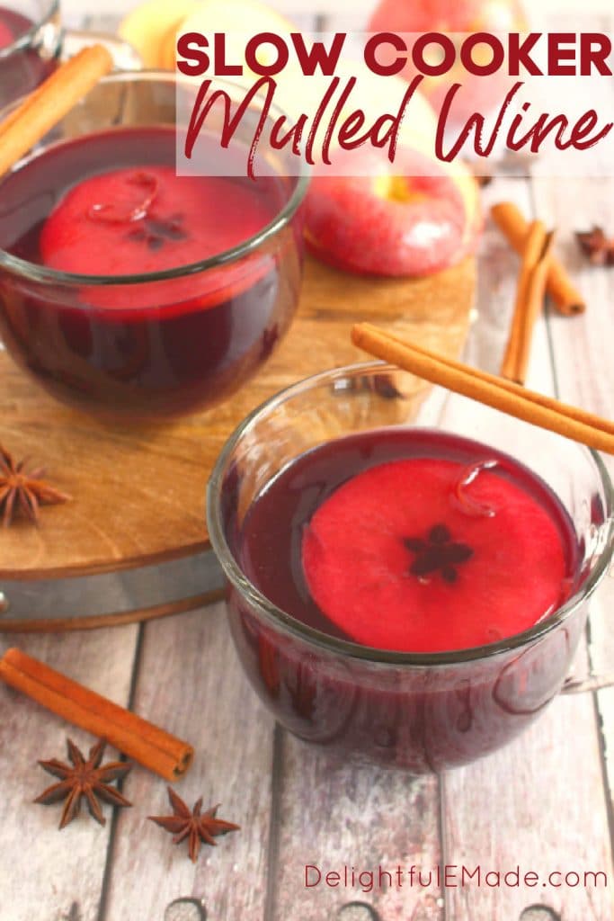 Slow cooker mulled win, in mugs with cinnamon sticks and apple slices.