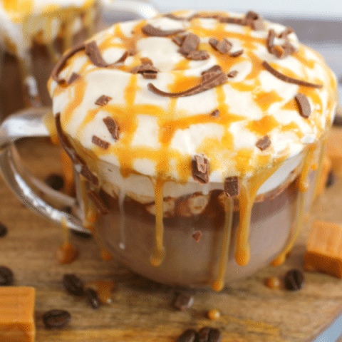 Homemade Starbucks salted caramel mocha in mug topped with caramel, whipped cream and chocolate curls.