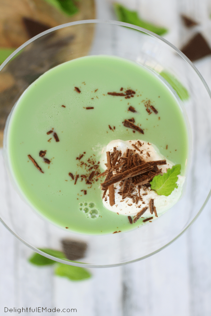 The top view of a mint martini garnished with chocolate shavings, whipped cream and a small mint leaf.