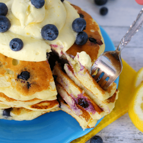 The fresh, delicious flavors of lemon and blueberry come together in these fluffy Lemon Blueberry Pancakes. Topped with a delicious lemon cream cheese whipped topping, and fresh blueberries, these make for an amazing breakfast or brunch!