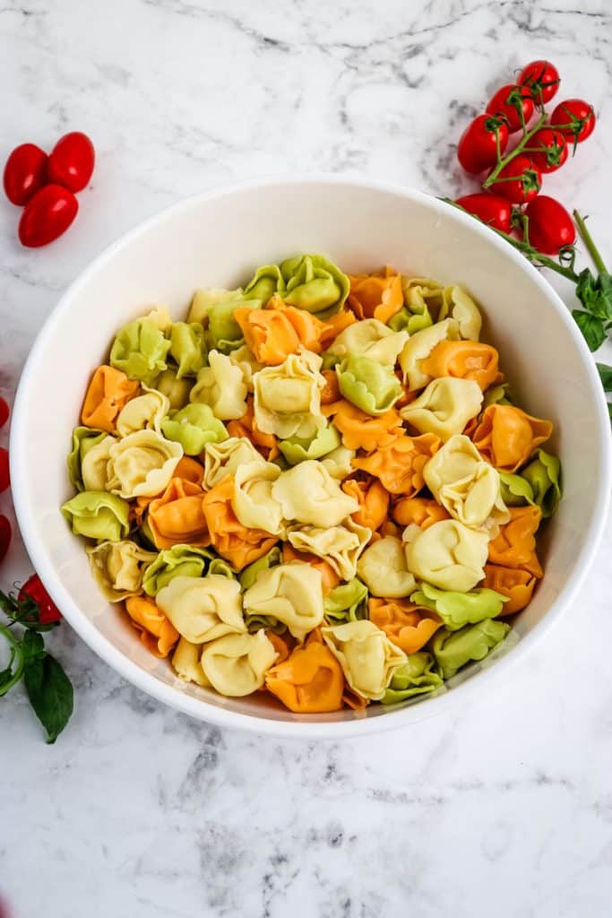 Cooked tri color tortellini pasta in a mixing bowl.