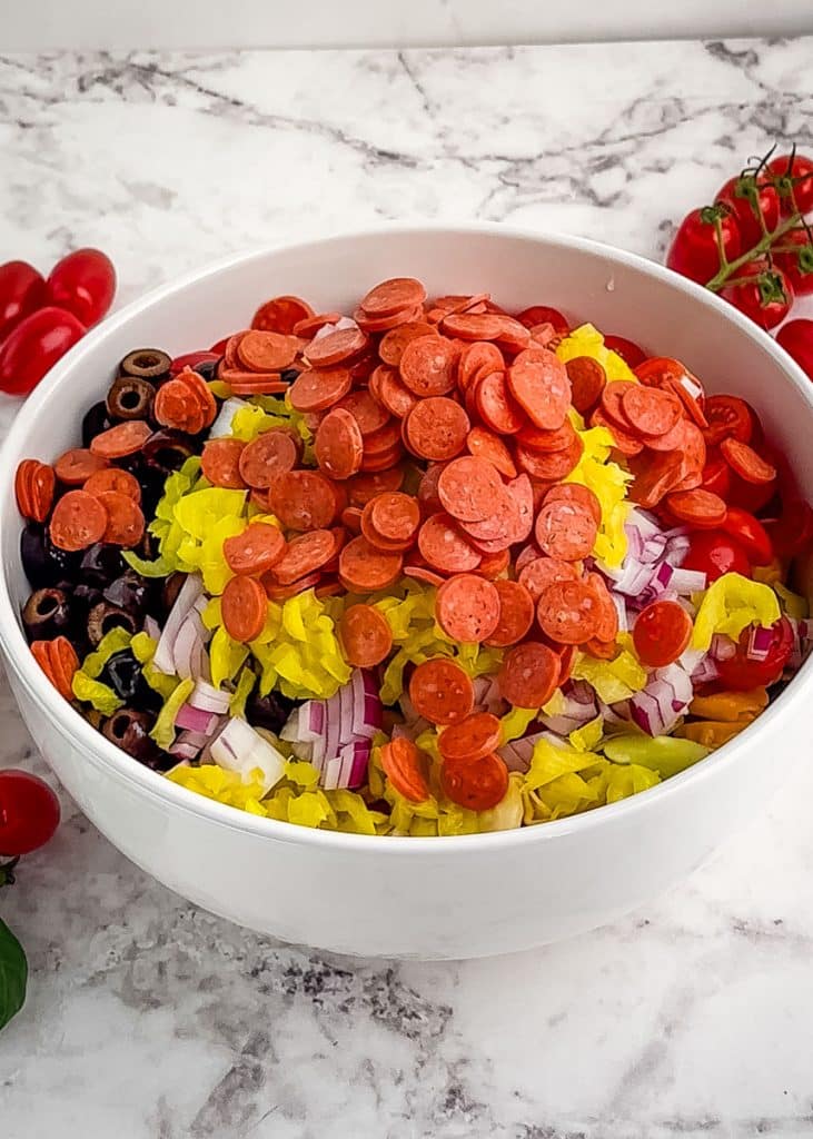 Italian tortellini pasta salad with all the ingredients in a large mixing bowl.
