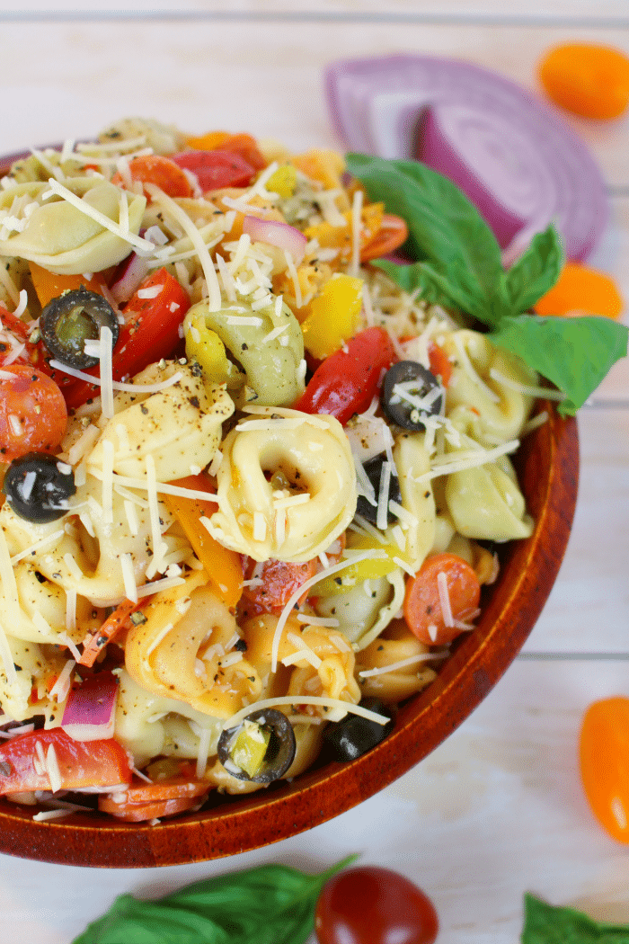 The perfect pasta salad for any pot-luck, picnic, cookout or backyard barbecue! This delicious tortellini salad is loaded with all of your Italian favorites, like salami, tomatoes, olives, banana peppers, red onion, and topped with Italian dressing and shredded Parmesan cheese! The ultimate side dish for any meal!