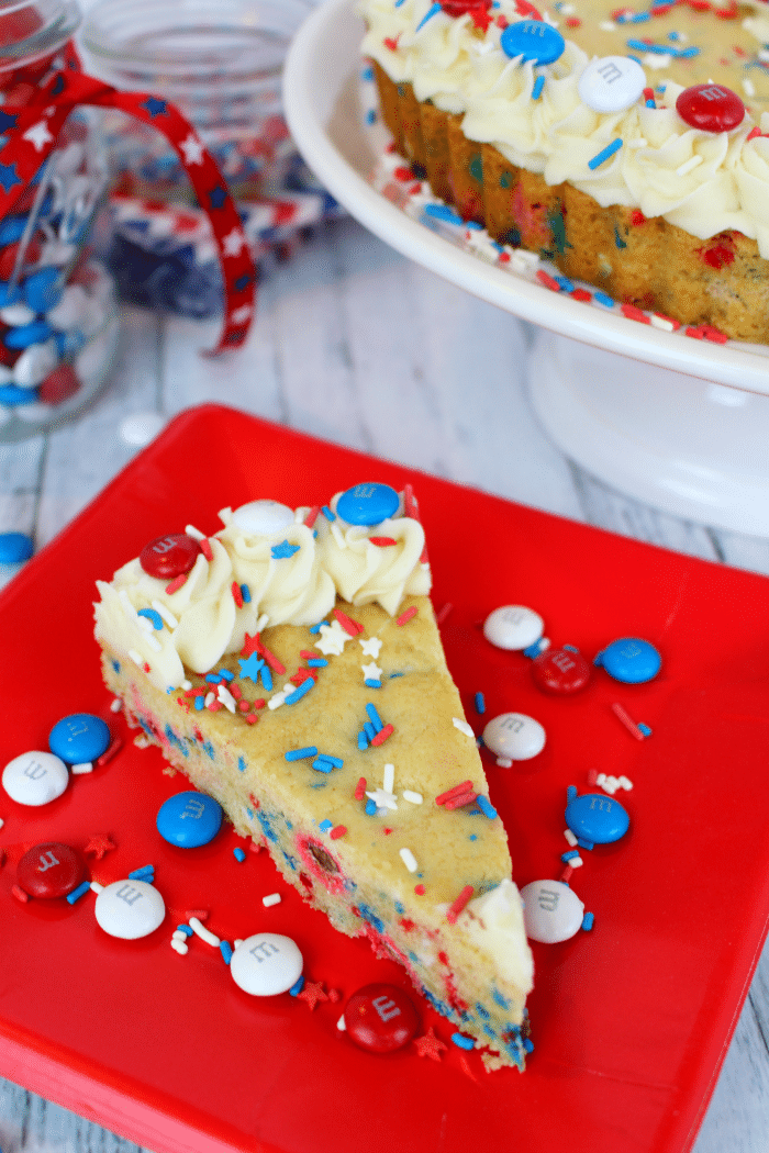 An amazing Red, White and Blue dessert, perfect for celebrating America! Chewy, delicious sugar cookie dough made with M&M's® Red, White, & Blue Milk Chocolate candies, stars and stripes sprinkles, and topped with buttercream frosting, makes for the ultimate patriotic treat! Fantastic for Memorial Day and 4th of July picnics and celebrations!