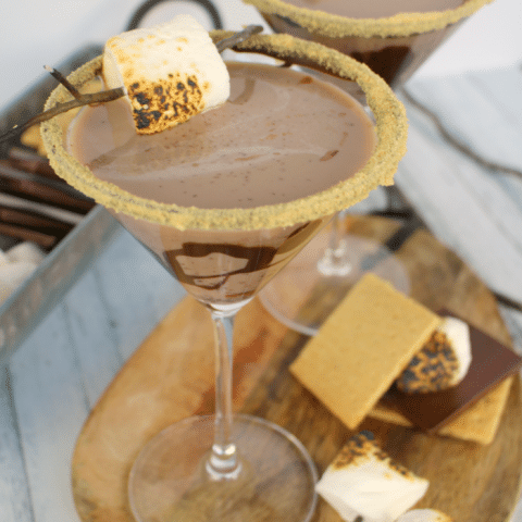All the amazing flavors of s'mores in one glorious cocktail! Made with marshmallow vodka, creme de cocoa, along with graham cracker crumbs, and toasted marshmallows, this drink will take you back to fun campfire memories, without the sticky fingers!