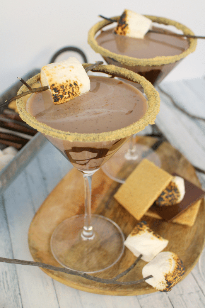 All the amazing flavors of s'mores in one glorious cocktail! Made with marshmallow vodka, creme de cocoa, along with graham cracker crumbs, and toasted marshmallows, this drink will take you back to fun campfire memories, without the sticky fingers!