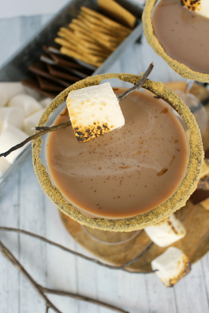 All the amazing flavors of s'mores in one glorious cocktail!  This fantastic summer cocktail is made with marshmallow vodka, creme de cocoa, along with graham cracker crumbs, and toasted marshmallows.  This drink will take you back to fun campfire memories, without the sticky fingers!