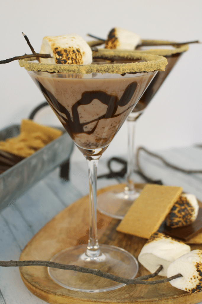 All the amazing flavors of s'mores in one glorious cocktail!  This fantastic summer cocktail is made with marshmallow vodka, creme de cocoa, along with graham cracker crumbs, and toasted marshmallows.  This drink will take you back to fun campfire memories, without the sticky fingers!