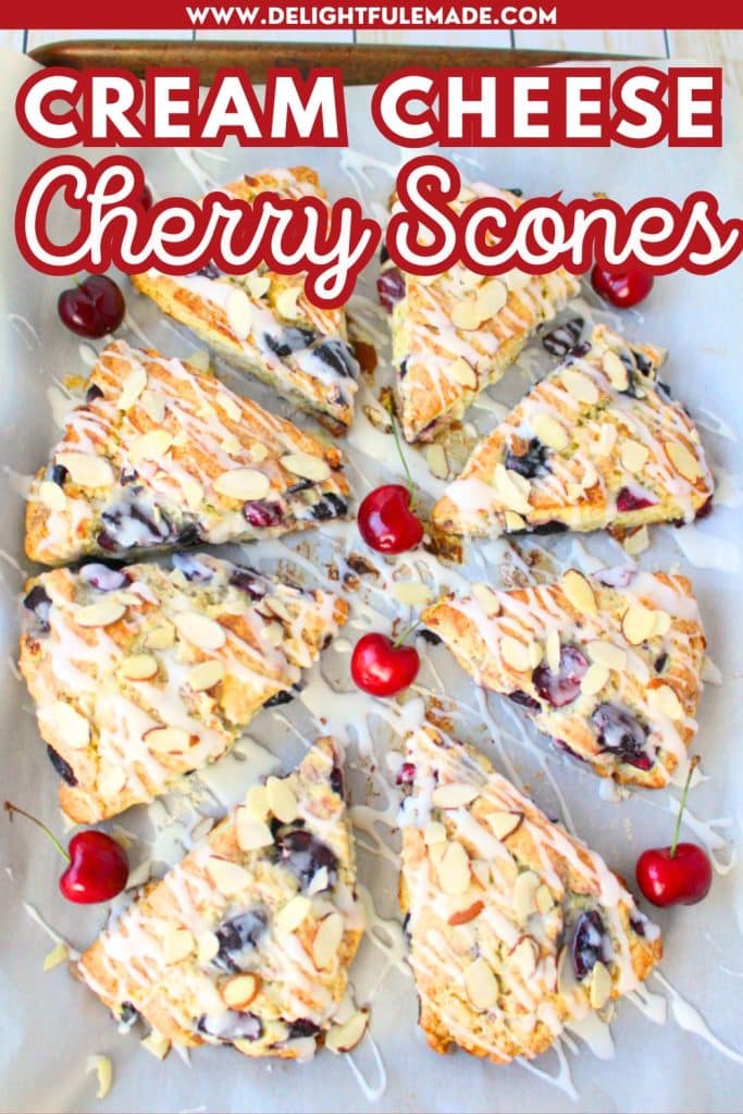 Glazed cherry scones garnished with fresh whole cherries laid out on a pan.