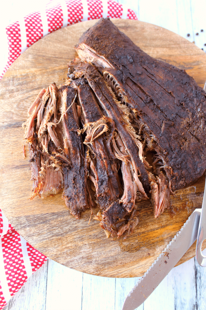 Slow cooker bbq beef on cutting board, being shredded.