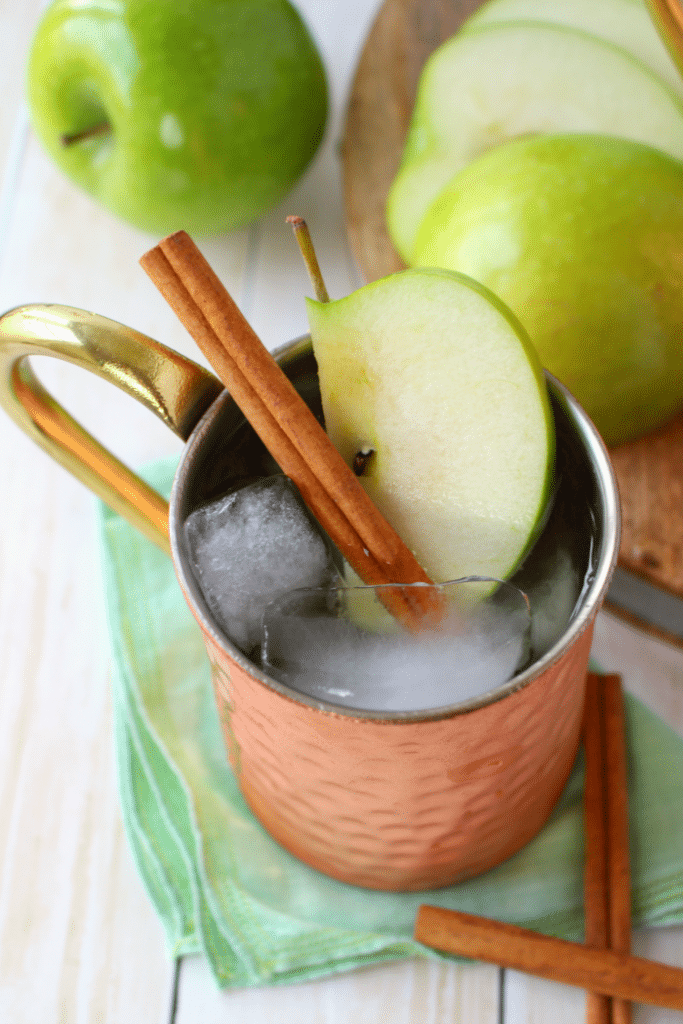 The perfect apple cocktail to enjoy on a crisp autumn day! My Apple Ginger Moscow Mule is made with spiced apple cider, Ginger liqueur, Ginger beer, and topped with a fresh, crisp Granny Smith Apple slice! How 'bout them apples?!
