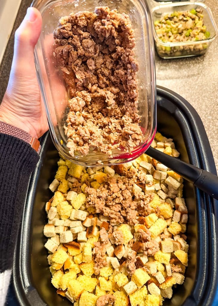 Browned sausage being added to stuffing cubes.