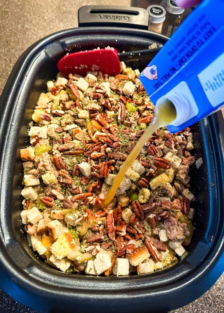 Broth being added to the stuffing ingredients in a slow cooker.