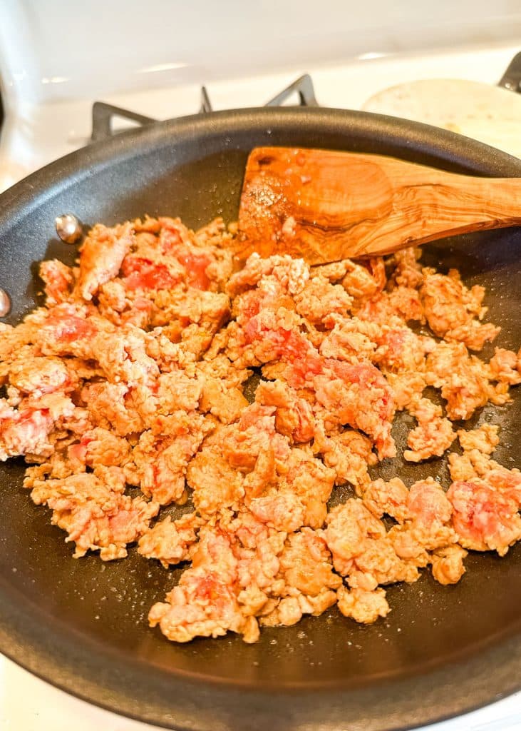Sausage being browned in a skillet.