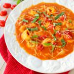 This fantastic tomato soup recipe has it all! Creamy, delicious tomatoes simmered together with Parmesan cheese, tender tortellini and topped with fresh basil, this soup is fantastic for the holidays or anytime you're looking to warm up on a cold night!