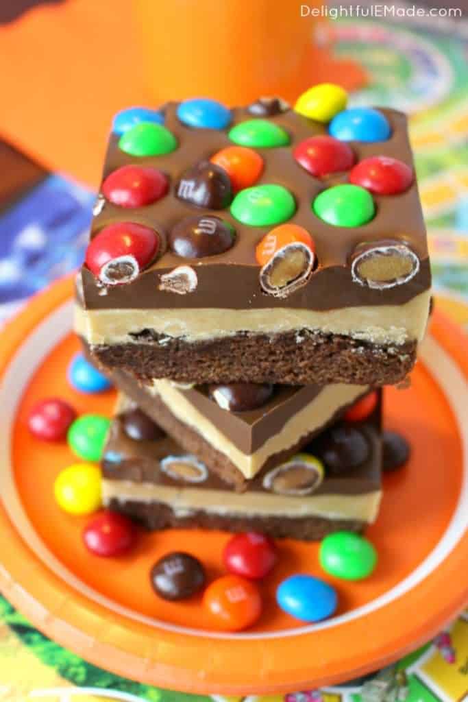 Stack of peanut butter brownies topped with peanut butter M&M's.