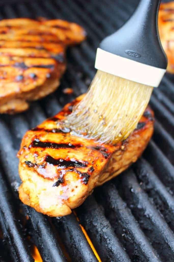 Chicken breasts on grill being brushed with balsamic marinade.