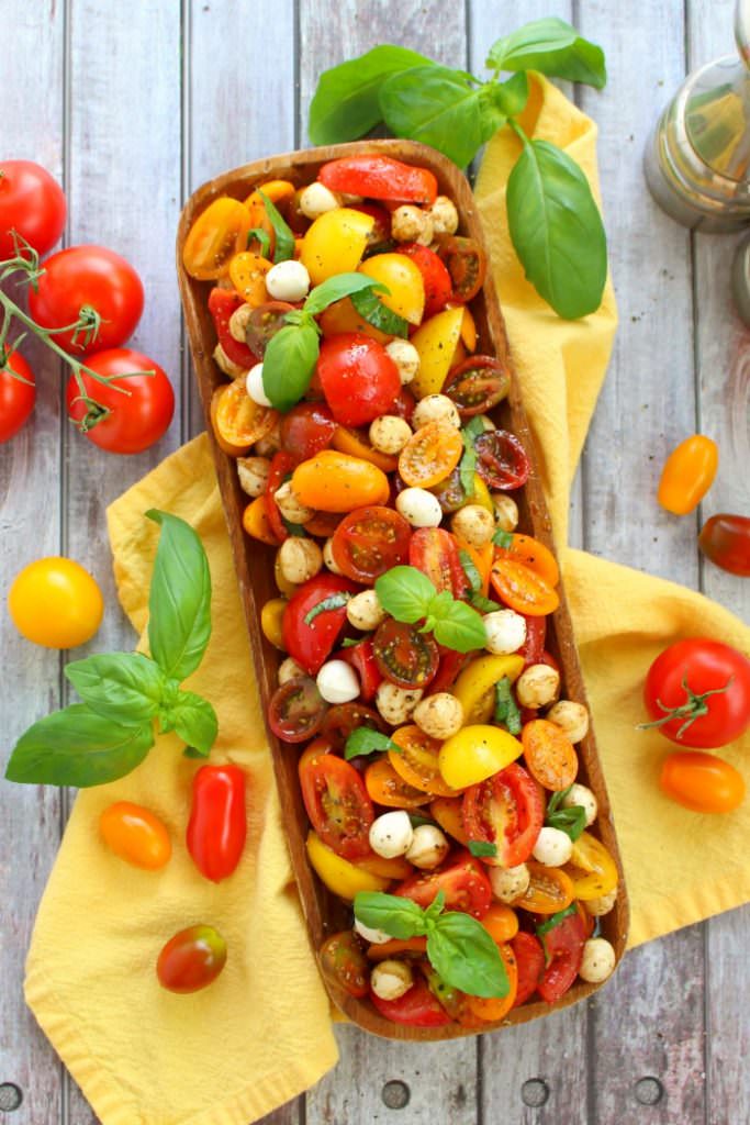 Italian caprese tomato salad on platter, garnished with basil.