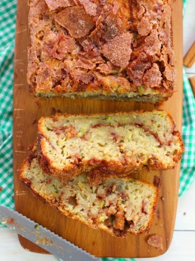 Cinnamon swirl zucchini bread on board, with two slices on their side.
