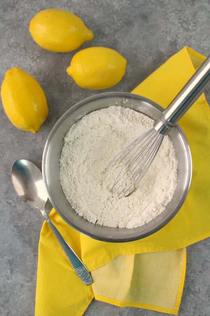 Dry ingredients for a lemon poppy seed cake recipe, in a mixing bowl with a whisk.