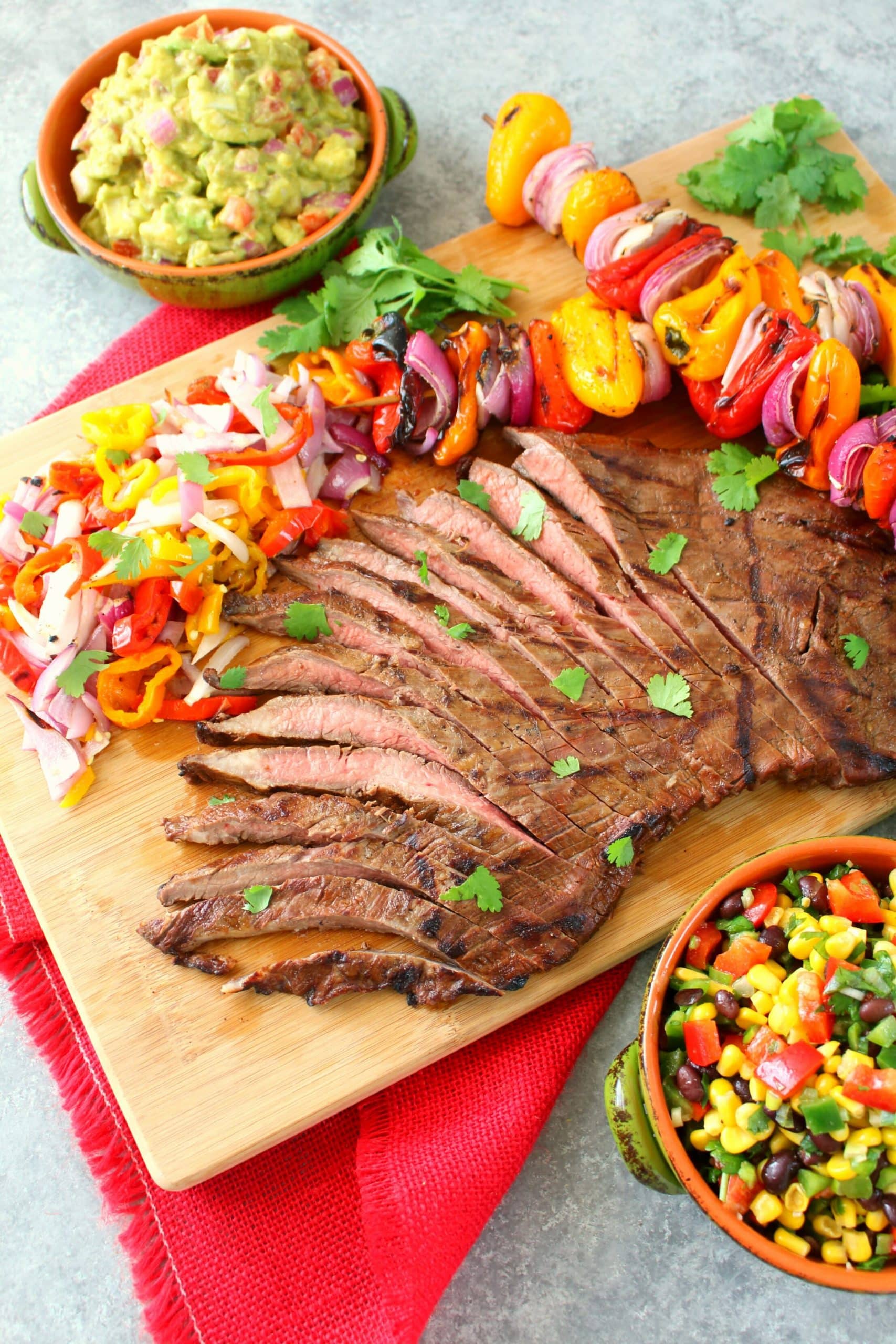 Grilled steak fajitas on cutting board with grilled peppers and onions.