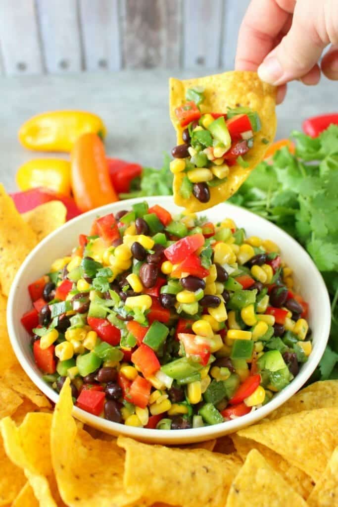 Perfect with your favorite tortilla chips, this delicious Southwestern Corn Salsa is amazing! Loaded with fresh, delicious veggies, this easy salsa recipe is just as flavorful as it is pretty. Fantastic as an easy appetizer for game day, and perfect for Cinco de Mayo!