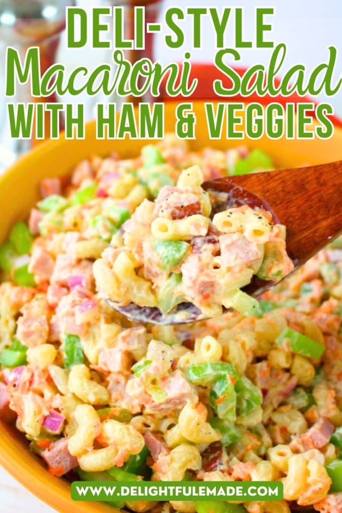 Bowl of macaroni salad with ham and vegetables with a spoon taking out a scoop.
